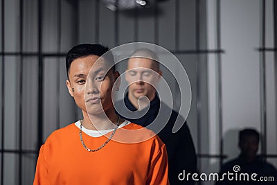 An Asian prisoner leaves his cell in the prison for transfer to another place of detention, accompanied by an armed Stock Photo