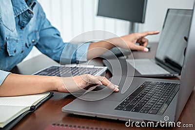 Asian programmer woman pointing and looking on multiple laptop screen to writing code and database Stock Photo
