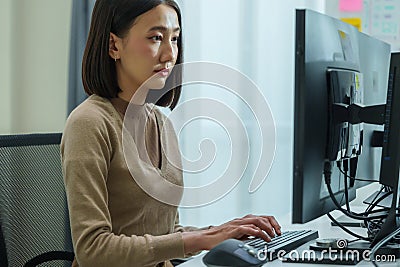Asian prompt engineer develop coding app with software data sitting in front of computer monitor at office Stock Photo