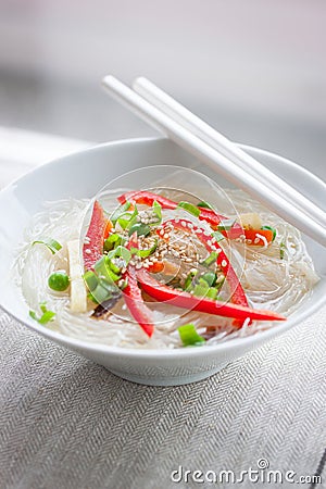 Asian rice noodles with vegetables and sesame in a bowl on a linen textile background Stock Photo