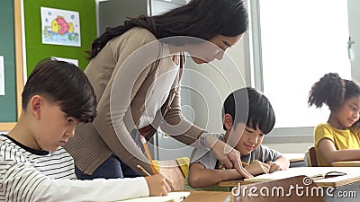Asian School Teacher Assisting Students in Classroom. Young Woman Working  in School Helping Boy with His Writing Stock Video - Video of asian,  lesson: 197363547