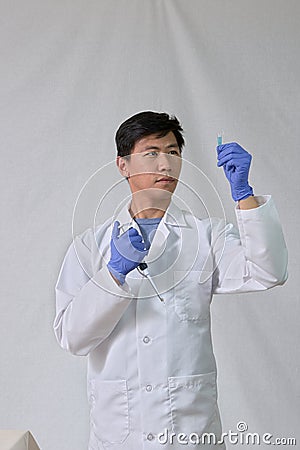 Asian scientist holding pipet and test tube Stock Photo