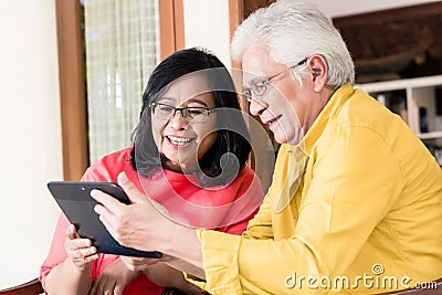 Asian senior couple in love smiling while holding tablet Stock Photo