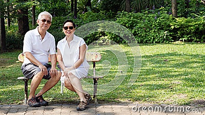 Asian senior couple sitting at bench in the park with copy space Stock Photo