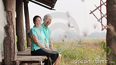 Asian senior couple sitting in the gazebo next to rice field Stock Photo