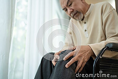 Asian Senior Elderly disabled man sit on wheelchair, suffering from injured leg at nursing home. Painful Mature Older male patient Stock Photo