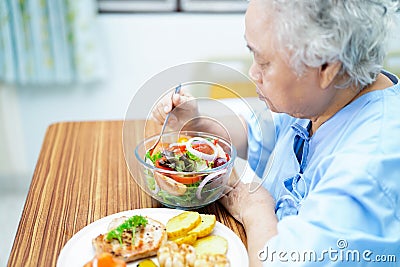 Asian senior or elderly old lady woman patient eating breakfast vegetable healthy food with hope and happy while sitting and Stock Photo