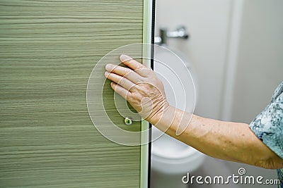 Asian senior elderly old lady woman patient open toilet bathroom slide door by hand Stock Photo