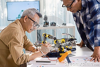 asian Senior engineer programming robot arm in automation and electronics technology lab Stock Photo