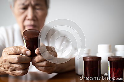 Asian senior grandmother reading medical information before taking of medicine,read the nutrition label on a bottle of vitamin Stock Photo