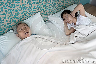 Asian senior grandmother snoring loudly open mouth feeling tired exhausted unhappy child granddaughter covering ears with both Stock Photo