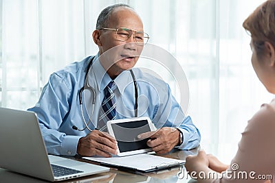 Asian Senior Male doctor in blue shirt talking with his patient Stock Photo