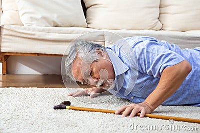 Asian senior man falling down on carpet and lying on the floor in living room at home. Stock Photo