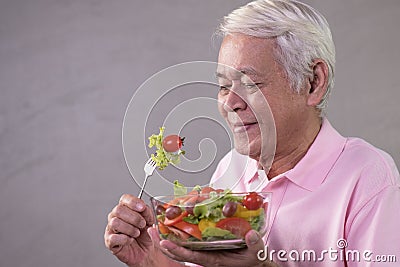 Asian senior man in joyful postures with hand holding salad bowl Stock Photo