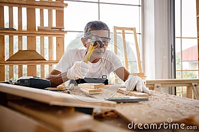 Asian senior man nail wooden board. Stock Photo