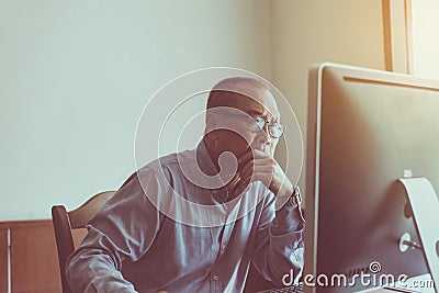 Asian senior man serious working and using computer at home in the morning Stock Photo