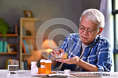 Asian senior man taking medicine at home Stock Photo