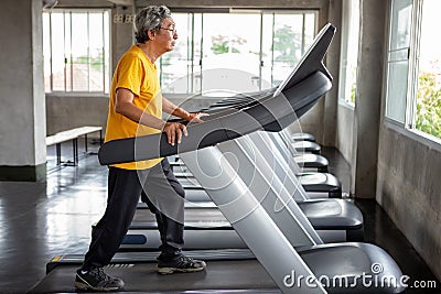 asian Senior man walking exercise on treadmill workout in fitness gym . sport , trainnig , retired , older , mature, elderly Stock Photo