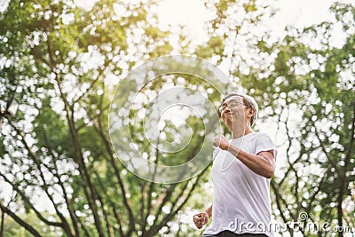 Asian senior mature man running Jogging In Park Stock Photo