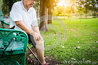 Asian senior woman arthritis,osteoarthritis,elderly people sitting,holding hand on the knee in park,feeling pain in the knee, Stock Photo