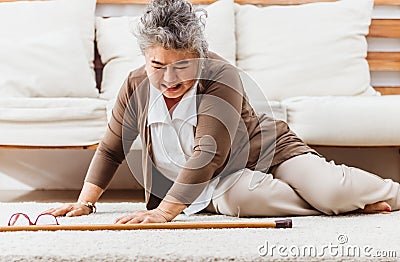 Asian senior woman falling down lying on floor at home alone. Elderly woman pain and hurt from osteoporosis sickness or heart Stock Photo