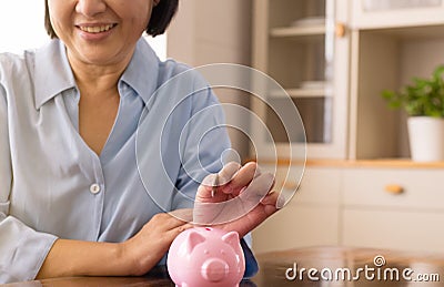 Asian senior female hands putting coin to piggy bank for retirement,Saving money concept Stock Photo