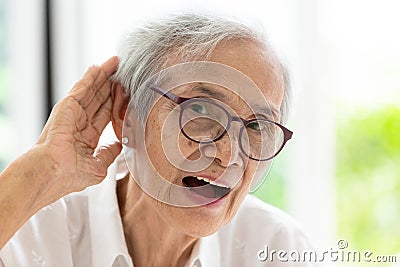 Asian senior woman listening by handâ€™s up to the ear,having difficulty in hearing,elderly woman hard to hear,wear glasses with Stock Photo