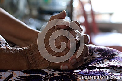 Asian senior woman sitting alone with wrinkles clenched hands on lap Stock Photo