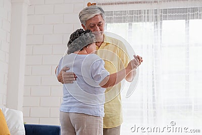 Asian seniors couple enjoy dancing in living room at home.aging at home concept Stock Photo