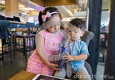 Asian siblings looks adorable having drinks at a local coffee shop stock photo Stock Photo