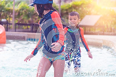 Asian siblings running and chasing in Swimming pool Stock Photo