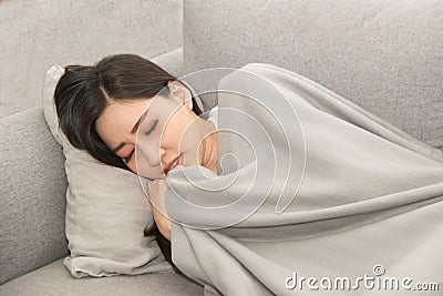 Asian Sick woman covered with a blanket lying in bed with high fever and a flu. Stock Photo