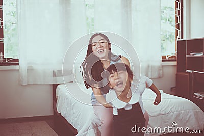 Asian single mom and carrying her cheerful daughter at home together,Happy and funny Stock Photo