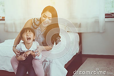 Asian single mom ticklish and carrying her cheerful daughter at home,Happy and funny Stock Photo