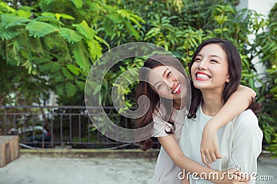 Asian sisters hugging and smiling in the park. Stock Photo