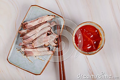 Asian sliced fried meat on a plate with sauce and chopstick Stock Photo