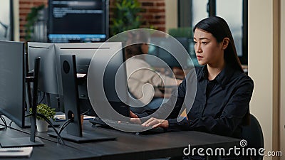 Asian software developer focused on writing code encounters unexpected compiling error sitting at desk Stock Photo