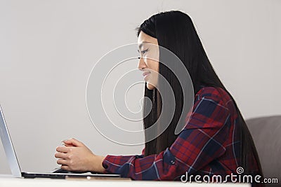 Asian student girl listening to speech on video call. Vietnamese BIPOC female studying online with laptop computer Stock Photo