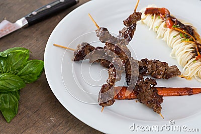 Asian style grilled teriyaki beef skewers on a white plate, top view. Delicious appetizer Stock Photo
