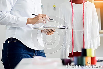 Asian tailor adjusts garment design on mannequin in workshop make a little adjustment to her work on model in the studio. Stock Photo