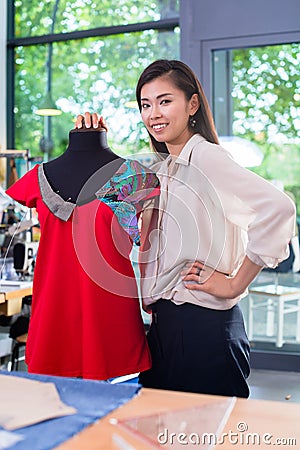 Asian tailor adjusts garment design on mannequin Stock Photo