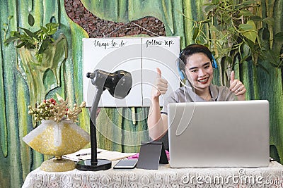 An asian teacher gives a double thumbs up to her online students. Concept of passing a student or giving approval. Stock Photo