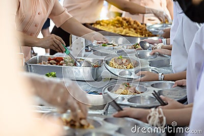 Asian teachers are distributing food to students,elementary school students are wait or queuing to receive free food,children Stock Photo