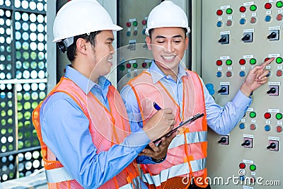 Asian technicians at panel on construction site Stock Photo