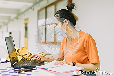 Asian teen woman working alone wearing face mask in university Stock Photo