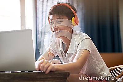 Asian teenage boy studying at home wearing headset and smiling Stock Photo