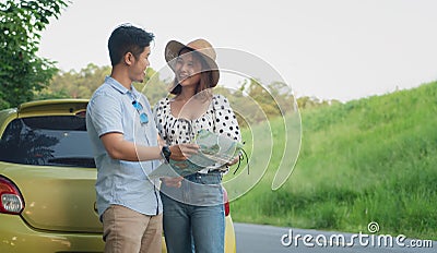 Asian teenage couples parked on the roadside, search for tourist spots on the map. Stock Photo