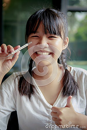 Asian teenager toothy smiling and holding body thermometer in hand Stock Photo