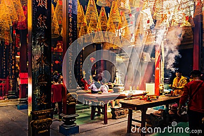 Asian Temple with beautiful sun rays shining through the ceiling lighting up the incense smoke. People praying in the Thien Hau Editorial Stock Photo