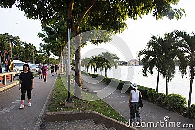 Asian thai people and foreign travelers walking jogging exercise biking bicycle on pathway around pondside in dusk time at Nong Editorial Stock Photo